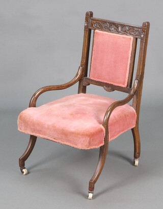 A Victorian carved simulated oak bar back nursing chair, the seat and back upholstered in pink dralon, raised on outswept supports with ceramic casters 76cm h x 49cm w x 47cm d 