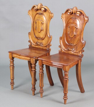 A pair of Victorian carved mahogany shield back hall chairs with solid seats of serpentine outline, raised on turned and fluted supports 96cm h x 40cm w x 34cm d  