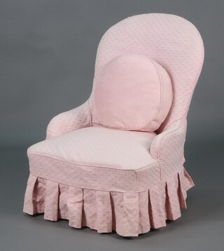 A Victorian tub back nursing chair upholstered in pink material with pink loose cover, raised on turned supports with brass caps and casters 78cm h x 59cm w x 49cm d 