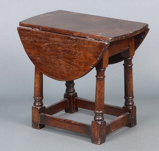 An oval oak drop flap occasional table raised on turned and block supports 45h x 50w x 27d 