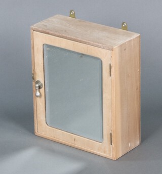 A pine hanging bathroom cabinet fitted a shelf enclosed by a bevelled plate mirror panelled door 35h x 30w x 13d 