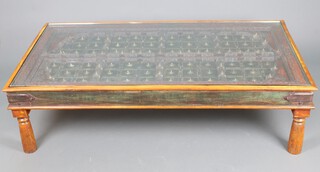 A carved Indian hardwood coffee table formed from a door with stud work decoration and glass plate top, raised on turned supports  45h x 165w x 94d  