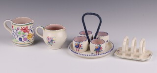 A Poole Pottery 4 piece egg cruet comprising stand 712 and 4 egg cups 713, 2 jugs with floral decoration daffodil 317 8cm and 678 9cm, 3 bar toast rack 992 5cm together with bowl with floral decoration 25cm and 5 preserve jars and covers