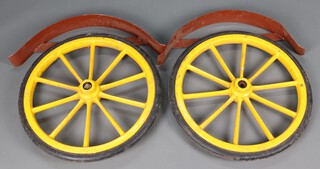 A pair of yellow fibre glass 10 spoked wheels with solid tyres together with mud guards 69diam. 