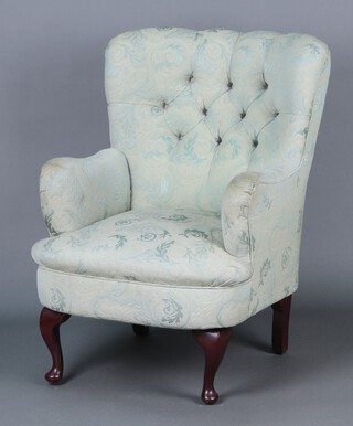 An armchair upholstered in green buttoned material, raised on cabriole supports 87h (some staining to arms) 