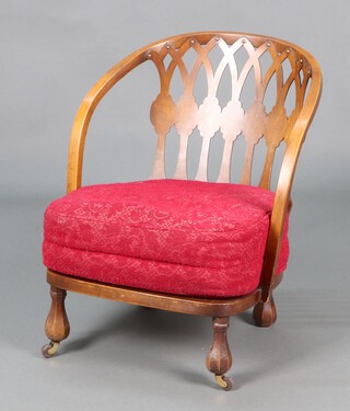 A 1930's pierced plywood and beech tub back nursing chair raised on pear shaped supports with casters 63cm h x 50cm w x 46cm d  