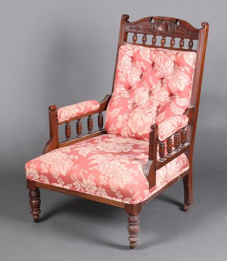An Edwardian carved walnut armchair with bobbin turned decoration, upholstered in pink and white floral material 95cm h x 66cm w x 66cm d 