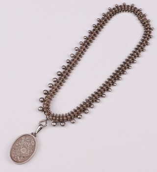 An engraved oval silver locket 13grams hung on a 45cm chain 