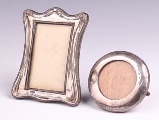 An embossed silver easel photograph frame Birmingham 1917, 12cm x 9cm and a circular silver ditto Birmingham 1921, 8cm 