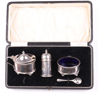 A silver 5 piece condiment set comprising mustard pot, salt, pepper and 2 salt spoons with blue glass liners  Birmingham 1928 and 1929 by Adie Brothers Ltd., 88 grams cased 
