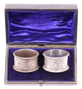 A cased pair of Victorian engraved silver napkin rings Birmingham 1897 by Hillard and Thomson, 57 grams