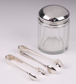 Two pairs of silver sugar tongs Birmingham 1921 and Sheffield 1931, together with a faceted glass pin jar with silver lid (dented) 48 grams 