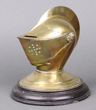 A 19th Century brass night light in the form of a knight's helmet, marked GM Depose, on a circular ebonised base 18cm h x 18cm diam.