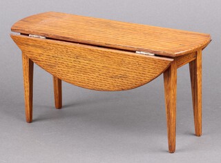 A model of a miniature oval oak drop flap dining table on square tapered supports 13cm h x 25cm w x 10cm d 