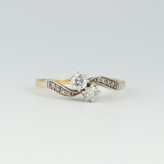 A gold marked 18ct and Plat. 2 stone diamond cross over ring, the shoulders both set 4 diamonds, size R 1/2, 2.9 grams