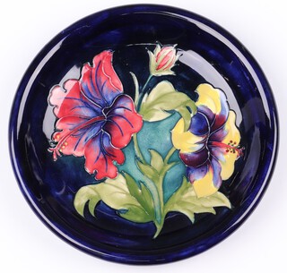 A Walter Moorcroft blue glazed hibiscus pattern plate, the reverse impressed Moorcroft and with Potter To The Queen label 22cm 