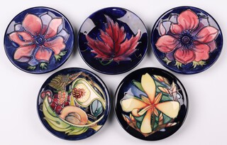 Two Moorcroft circular blue ground anemone dishes, a Moorcroft blue ground Autumn Leaf dish, a Moorcroft Queens Choice dish designed by Emma Bosson, the reverse dated 30 11 02 and signed, 12 cm and a Moorcroft Panache dish designed by Sian Leeper for the Moorcroft Collectors Club  dated 2004 12cm 