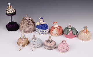 Ten 1920's porcelain headed pin cushion dolls, some with legs