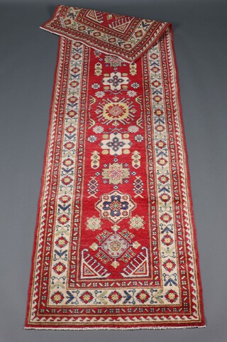 An orange, green and white ground Persian runner with 9 stylised medallions to the centre 288cm x 81cm 