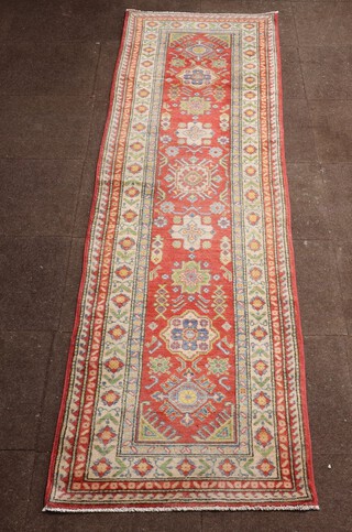 An orange, yellow and green ground Caucasian style runner with 9 stylised octagons to the centre within a multi row border 304cm x 79cm 