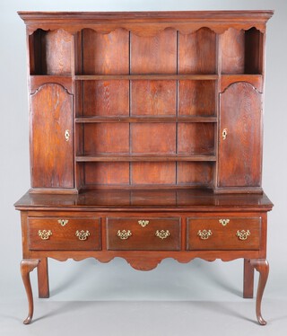 A Georgian oak dresser, the raised back with moulded cornice and 3 shelves flanked by cupboards fitted a shelf and drawer enclosed by panelled doors, the base with wavy apron and 3 long drawers, raised on cabriole supports 207cm h x 168cm w x 54cm d 