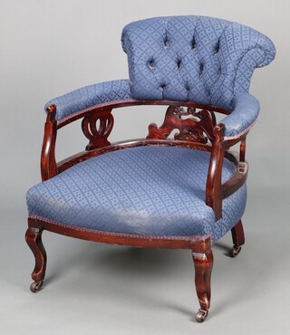 An Edwardian carved and pierced mahogany tub back chair upholstered in blue buttoned material, raised on cabriole supports 72cm h x 59cm w x 57cm d 