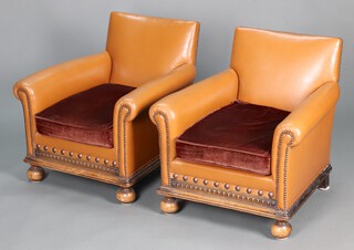 A pair of 1930's club style armchairs upholstered in brown material, raised on bun feet 69cm h x 69cm w x 66cm d 