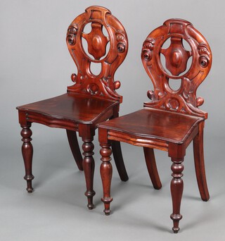 A pair of Victorian mahogany hall chairs with pierced shield shaped backs and solid seats of serpentine outline, raised on turned supports 84cm h x 43cm w x 34cm d 