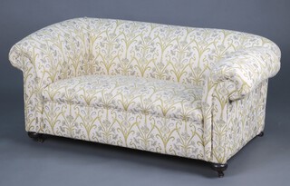 A Victorian 2 seat drop arm Chesterfield sofa upholstered in green and white floral patterned material 61cm h x 146cm w x 76cm d 