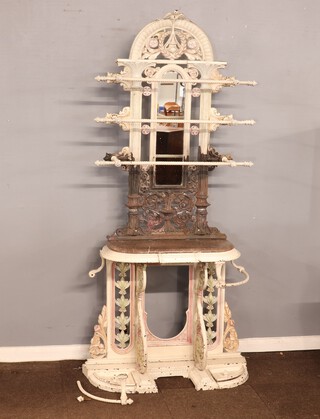 In the manner of Coalbrookdale, an impressive Victorian pierced cast iron hall stand, the raised arched back surmounted by a figure of a dove with garlands and with arched plate mirror to the centre behind 3 rails, having a D shaped marble base, the base fitted a drawer with stick stand to the side 204cm h x 81cm w x 42cm d