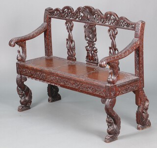 A 19th Century Anglo Indian heavily carved and pierced hardwood settle, the raised back carved entwined peacocks and elephants, on shaped supports 97cm h x 121cm w x 47cm d 