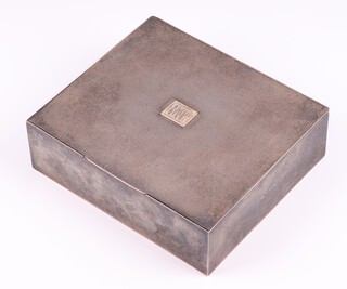 A silver engine turned table top cigarette box with gold plaque monogrammed B.N.W. Birmingham 1935 by A Wilcox 5cm h x 16.5cm w x 14.5cm d.  The interior containing a broken cigarette and a scrap drawing marked "and parts broken mower bits -/10/74"  