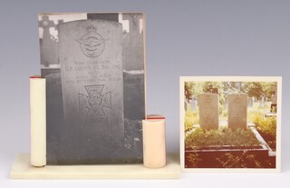A black and white photograph of the grave of Wing Commander Guy Penrose Gibson VC DSO DFC, contained in a cream and red Bakelite table frame 15cm x 15cm x 5cm, the grave is situated in the Roman Catholic Cemetery at Steenbergen-en-Kruisland, Netherlands.  The photograph is visible in photos of Sir Barnes Wallis' office on top of a bookcase.  A colour photo of the pair of graves of Gibson and his navigator, Squadron Leader Jim Warwick DFC, was found in the frame and is also included.  Gibson and Warwick died on 19th September 1944 when their Mosquito aircraft crashed in Holland.   