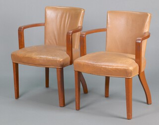A pair of 1930's oak open arm chairs, the seats and backs upholstered in brown leather, raised on square supports 84cm h x 61cm w x 63cm d (seat height 48cm) 