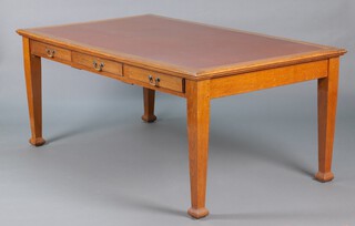 A 1920's light oak library table with brown inset writing surface above 3 long drawers, raised on square supports 77cm h x 182cm w x 106cm d 