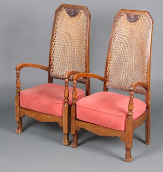 A pair of 1930's beech framed high back open arm chairs, the backs with cane panels 106cm h (1 arm glued) 