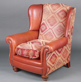 A winged armchair upholstered in Kilim patterned and brown material, raised on bun feet