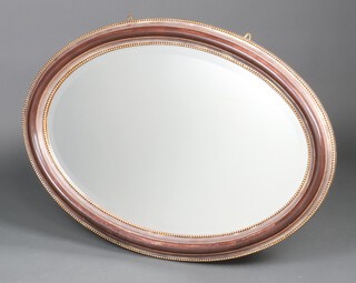 A Victorian style oval bevelled plate wall mirror contained in a brown and gilt ball studded frame 70cm x 99cm 