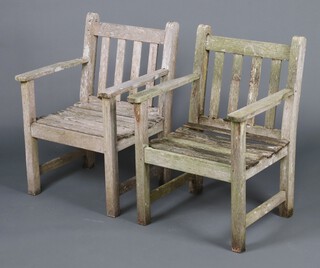 A pair of well weathered slatted wooden garden armchairs 82cm h x 59 cm w x 55cm d 