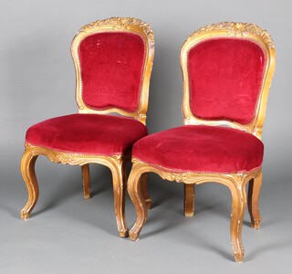 A pair of French style gilt painted salon chairs, the seats and backs upholstered in red material, raised on cabriole supports (1 a/f)