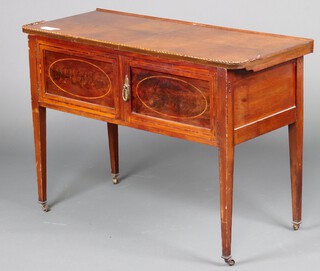 An Edwardian inlaid mahogany wash stand enclosed by pair of panelled doors, with later walnut top, raised on square tapered supports, brass caps and casters 74cm h x 111cm w 45cm d 
