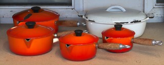 A Le Creuset white enamelled twin handled casserole dish, and 4 burnt orange saucepans (some chips) 