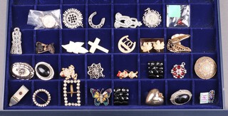 A collection of costume jewellery including a brooch in the form of a butterfly, marcasite brooch, etc, contained in a shallow display case