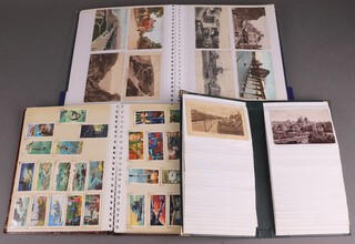 Three albums of black and white and coloured postcards together with a small collection of cigarette cards 