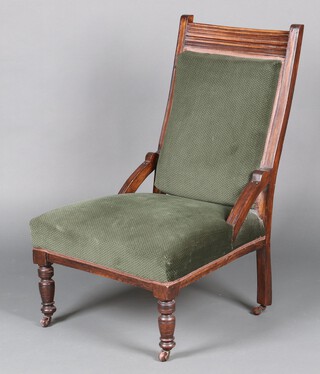 An Edwardian carved mahogany nursing chair, the seat and back upholstered in green material, raised on turned supports 
