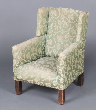 A child's 1930's winged armchair upholstered in green material  