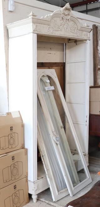A 19th Century white painted armoire with carved cornice, the interior enclosed by a pair of arch panelled doors, raised on turned supports 231cm h  (missing bolts) 