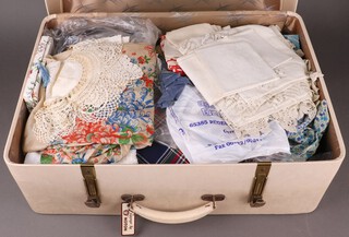 A 1950's white suitcase containing a collection of linens 