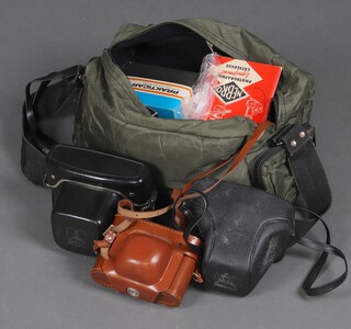 A collection of vintage SLF cameras contained in a camera bag to include an Ilford Sportsman, a Praktica LLC, a Praktica MTL3 and a Praktica macro lens 