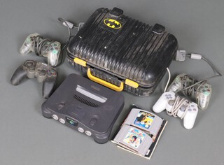 A collection of retro video game items to include a Nintendo 64 base unit, a collection of generic Play Station controllers, 2 Nintendo 64 games (unboxed) - Snowboard Kids, 007 The World is Not Enough contained in a Batman plastic carry case 
